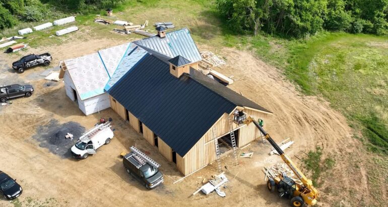 Commercial roofing project with black metal roof panels being installed